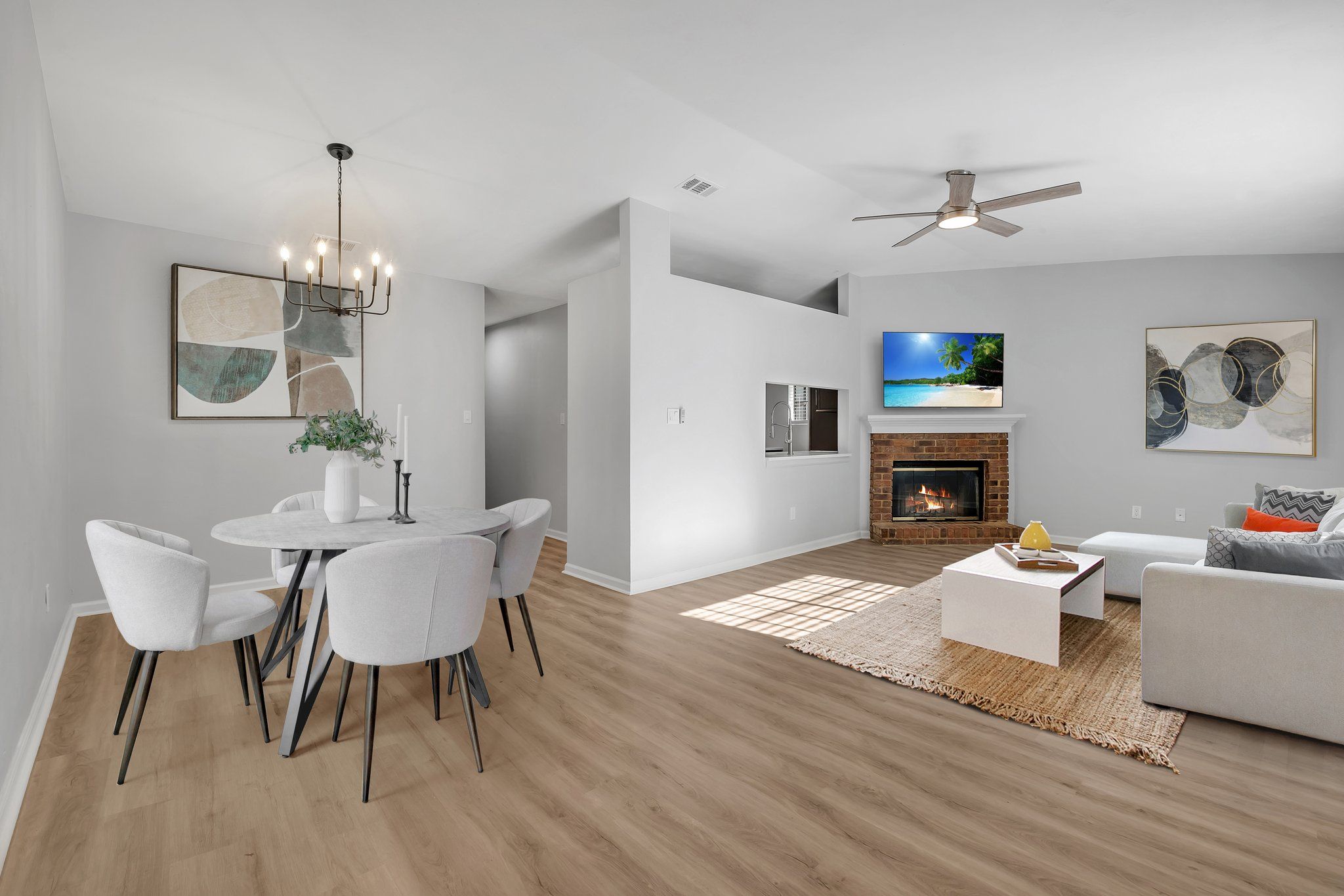 Open living and dining room, staged, with a brick wood-burning fireplace and wide-plank flooring