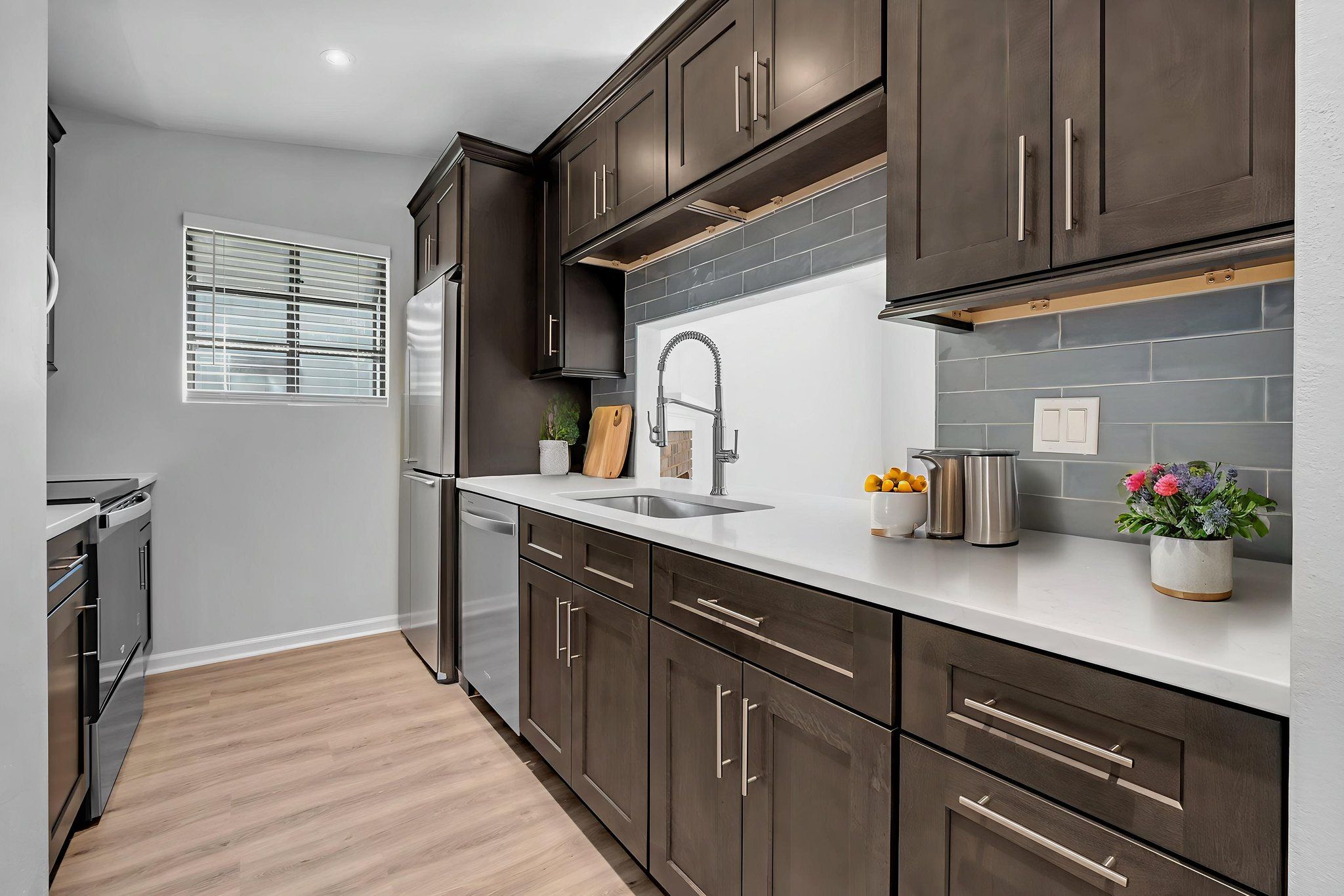 Remodeled kitchen with dark shaker cabinetry, white quartz counters, and a slate-blue tile backsplash