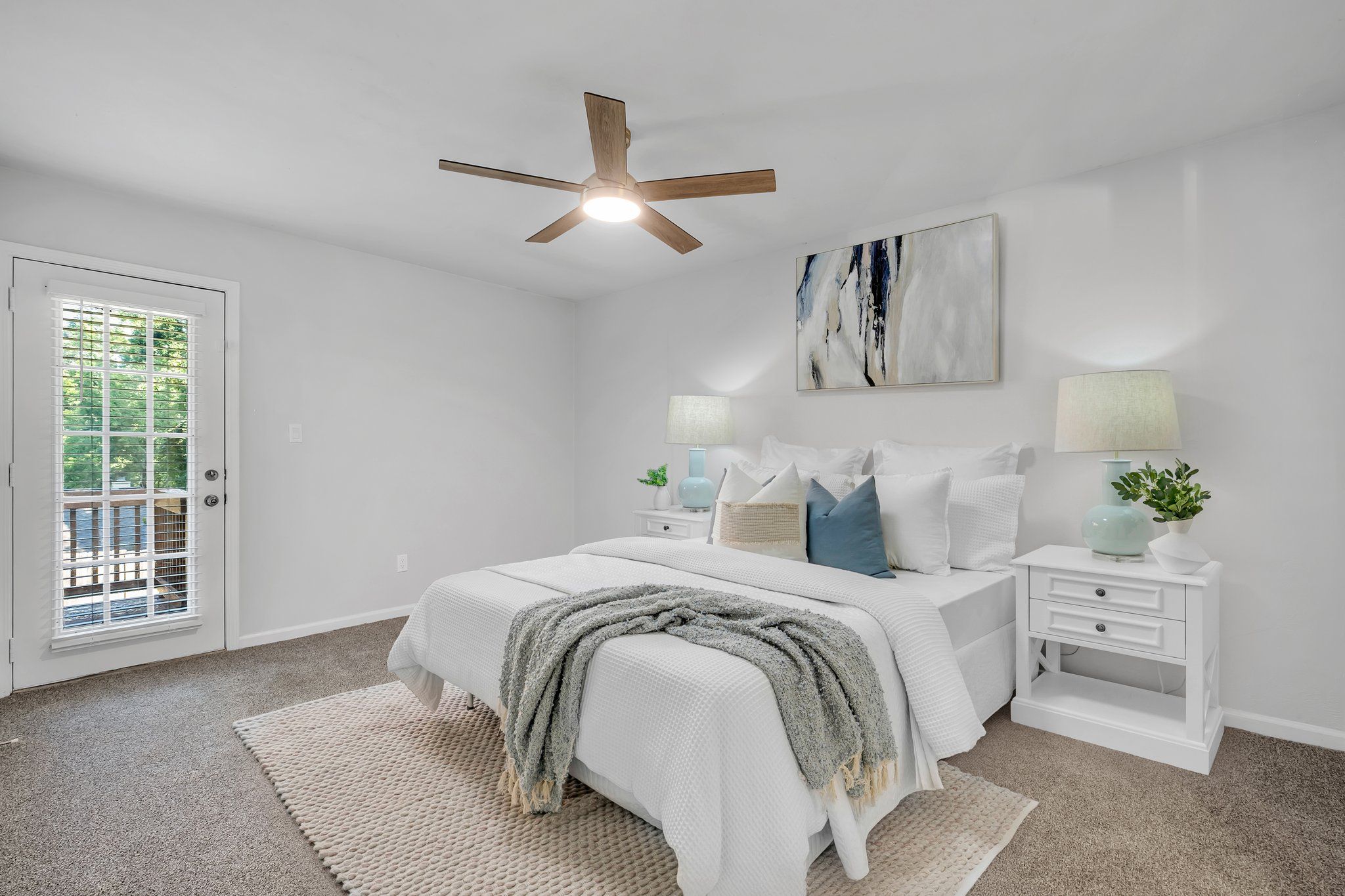 Primary bedroom, staged, with a ceiling fan and a French door opening to the back deck